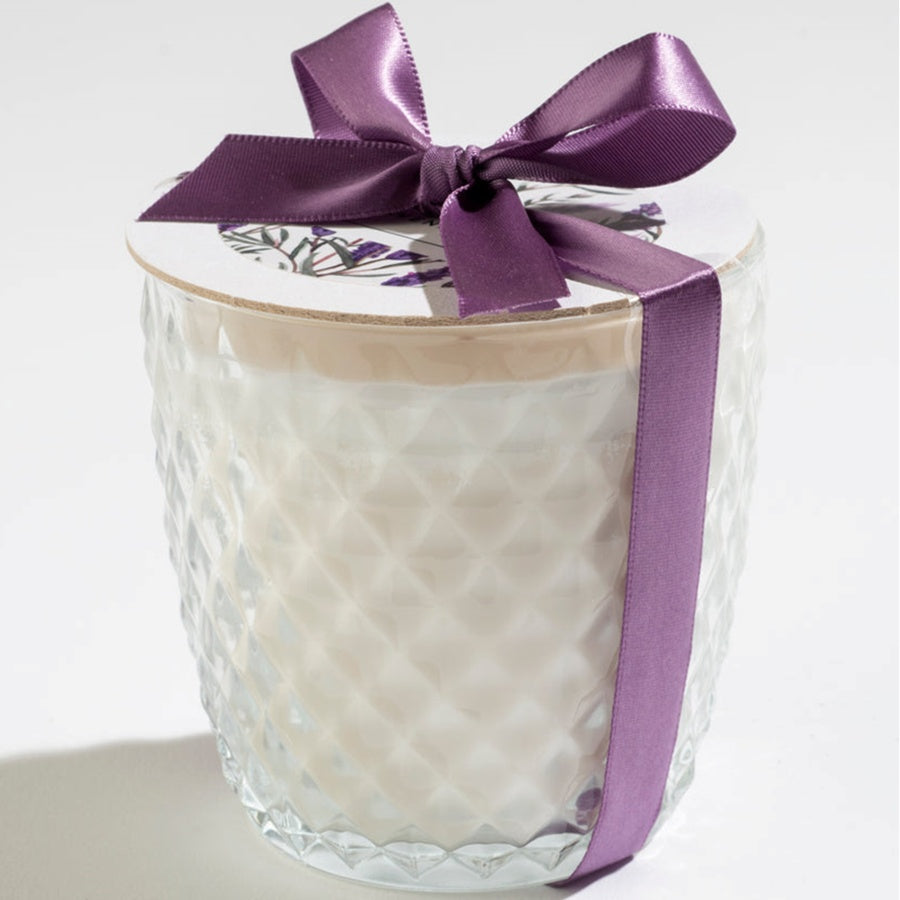 Glass candle with a purple ribbon on a white background