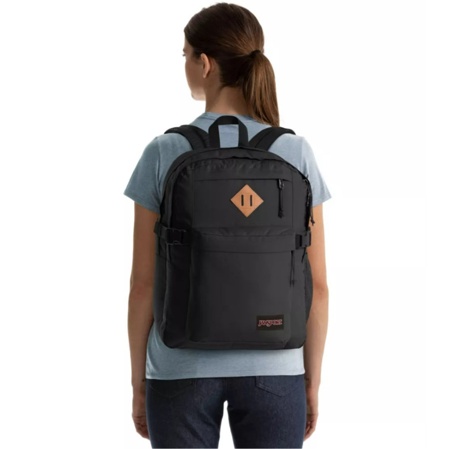 Person wearing a black Jansport backpack with a brand logo on a white background