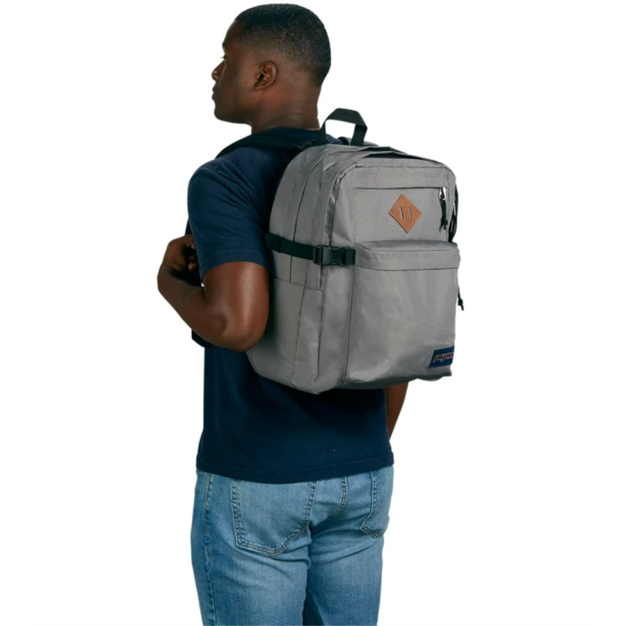 Man wearing a gray Jansport backpack on a white background