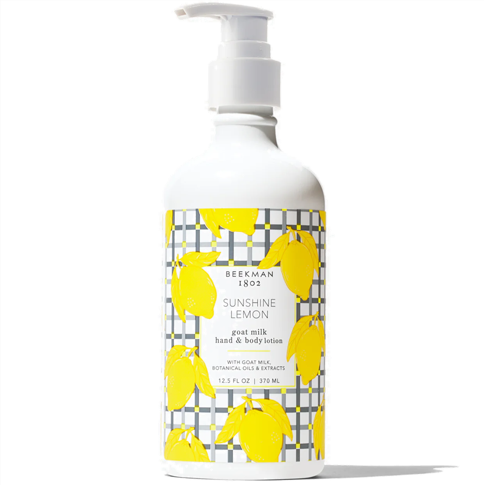 Bottle of Beekman 1802 Sunshine Lemon goat milk hand & body lotion with yellow lemon illustrations on a white background.