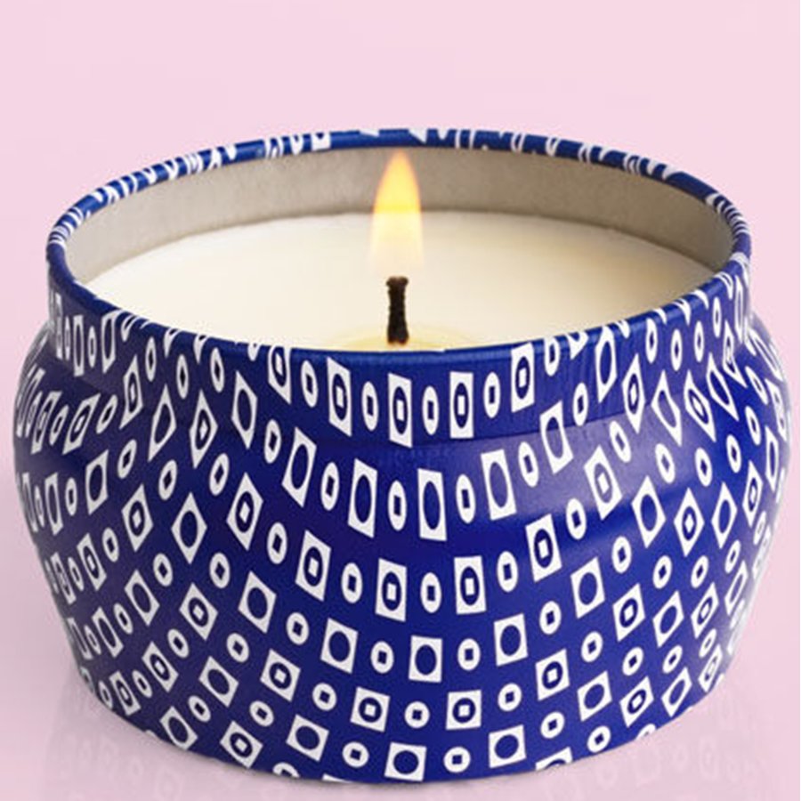 Candle in a blue container with white geometric pattern on a pink background