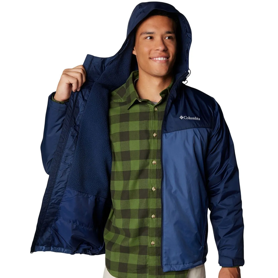 Person wearing a blue Columbia jacket over a green plaid shirt on a white background