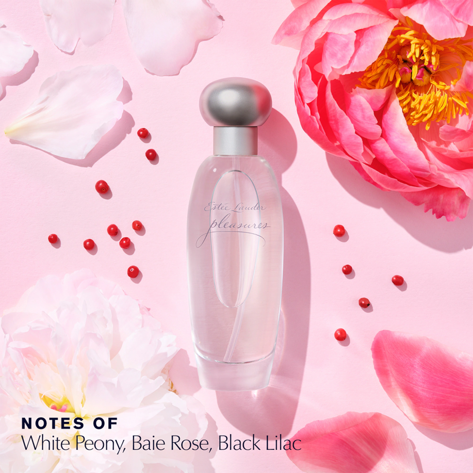 Perfume bottle with pink flowers and petals on a pink background