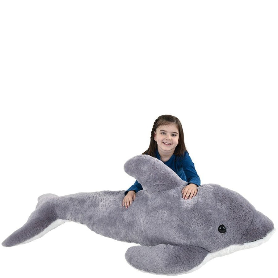 Child sitting on a large gray plush dolphin toy against a white background