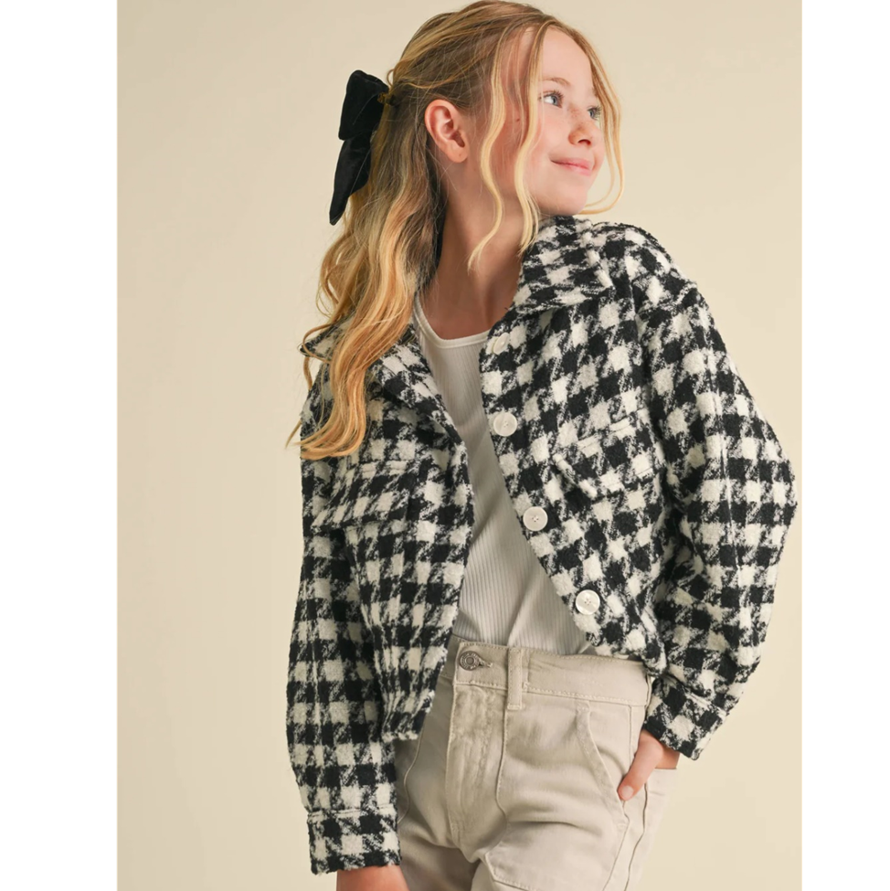 Young girl wearing a black and white checkered jacket on a beige background