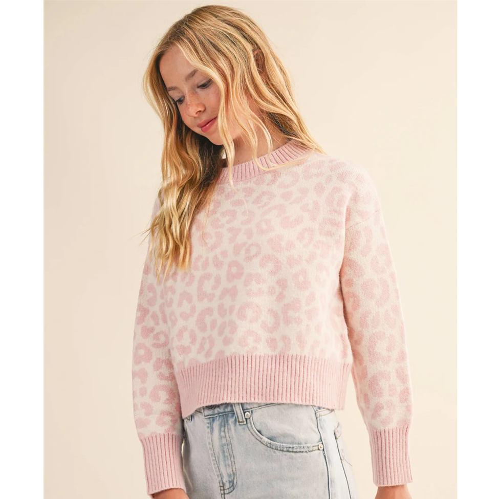 Girl wearing a pink sweater with a subtle pattern on a beige background