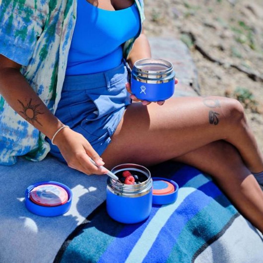 Person sitting outdoors with blue containers on a towel