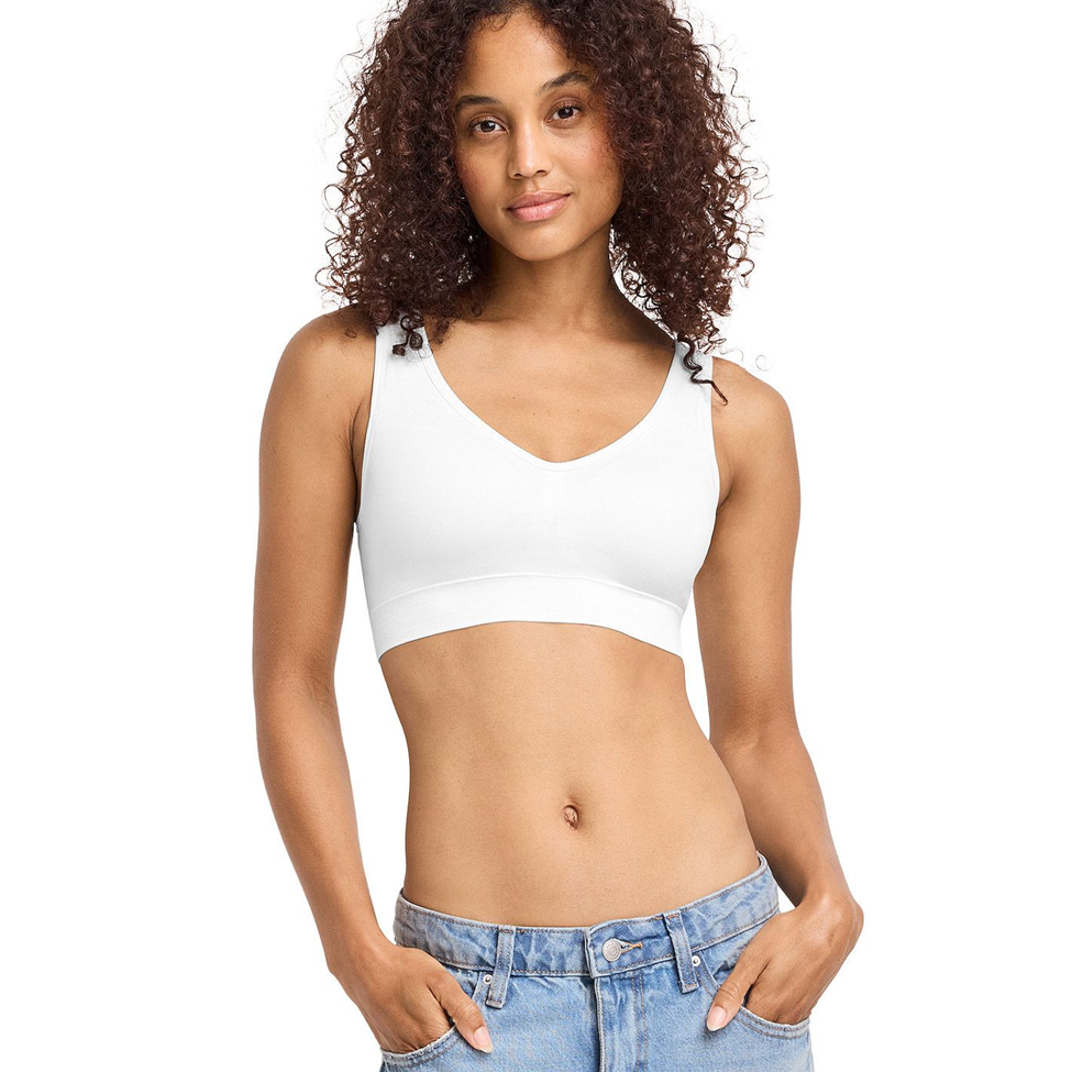 Woman wearing a white sports bra and blue jeans on a white background