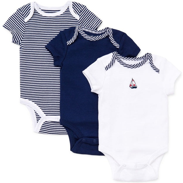 Three baby bodysuits in navy, white with stripes, and white with a sailboat design on a white background.