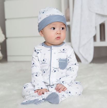 Photo of Baby sitting in a onesie and hat set with puppy pattern on the carpet