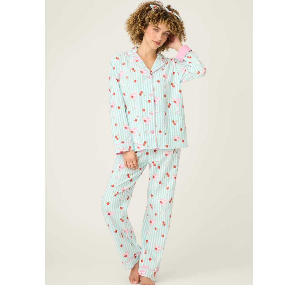 Woman wearing a light blue pajama set with cherry pattern on a beige background