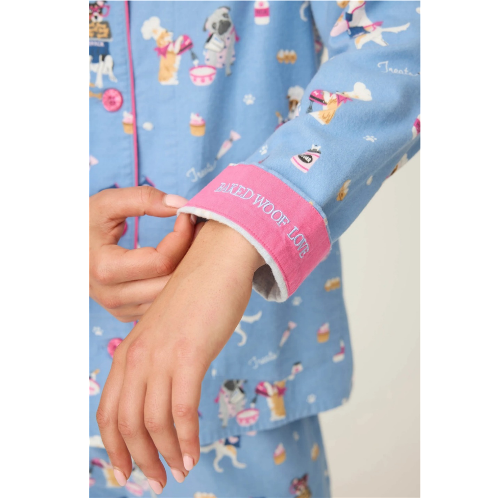 Close-up of a child's arm wearing a blue pajama with dog pattern and pink cuffs.