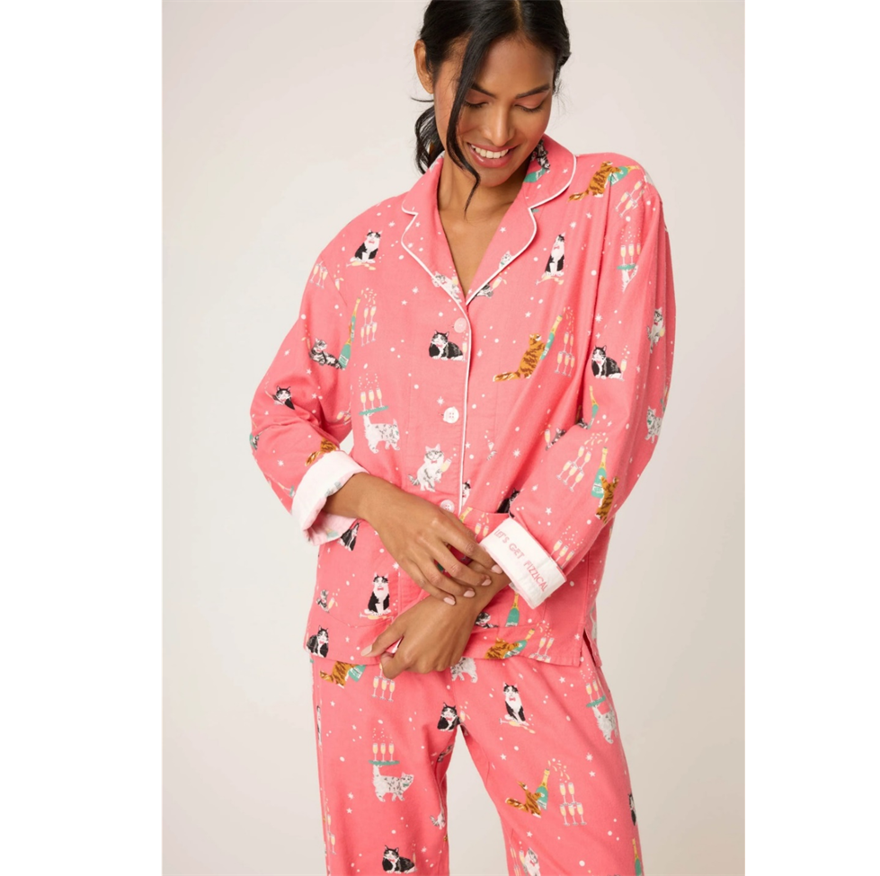 Woman wearing pink pajamas with animal prints on a plain background