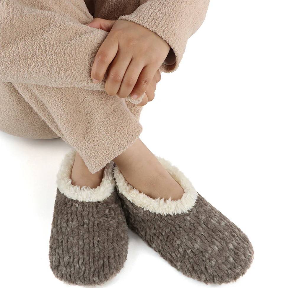 Person wearing brown fuzzy slippers on a white background