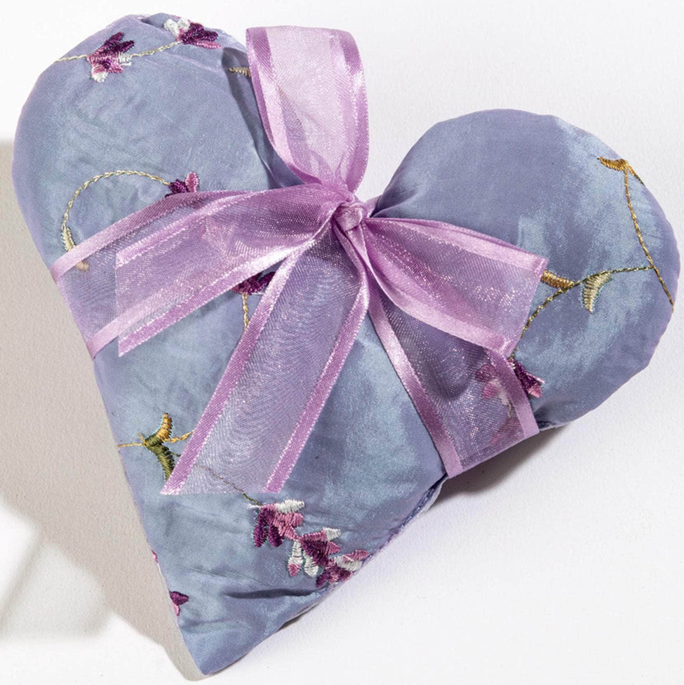 Heart-shaped pillow with floral patterns and a purple ribbon on a white background