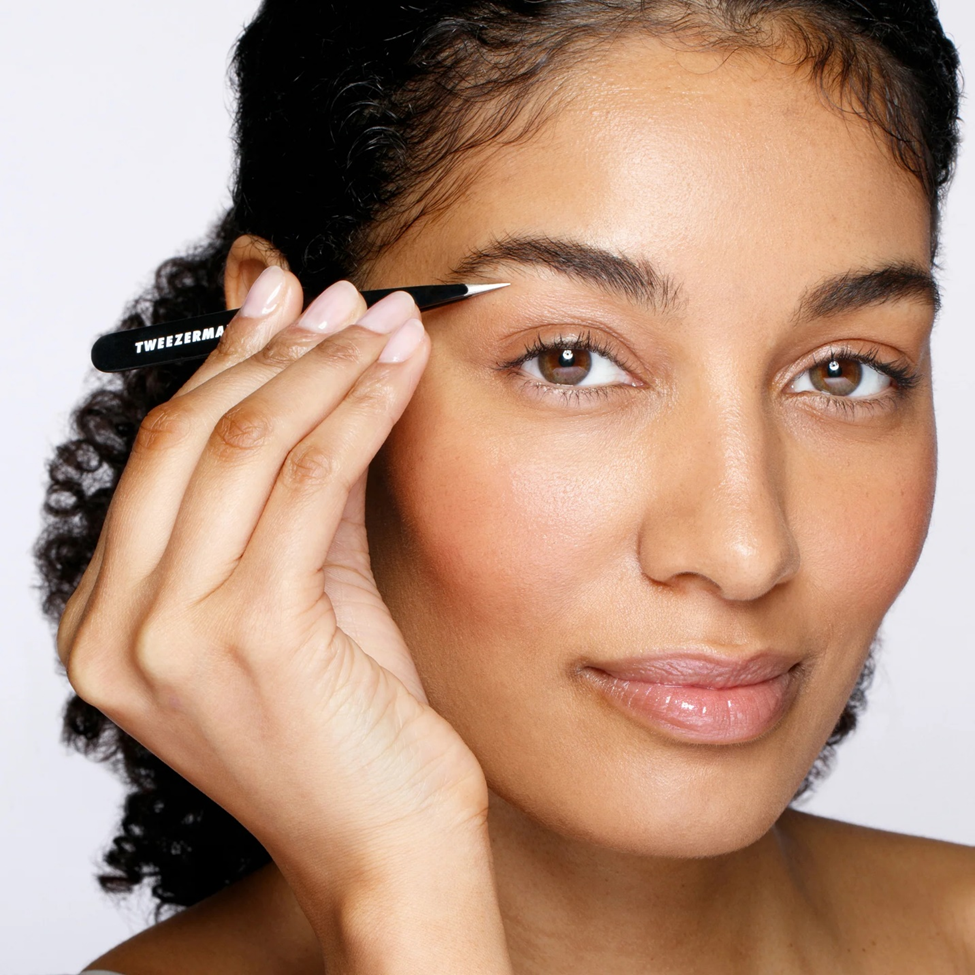 Woman applying makeup with a brush on a white background