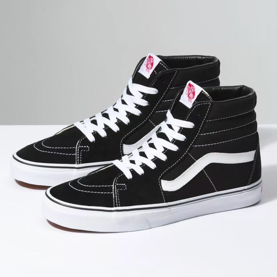 Black and white sneakers with a prominent brand logo on a light gray background