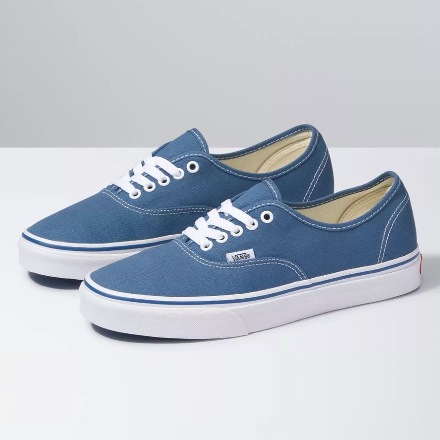 Pair of blue sneakers with white laces on a gray background