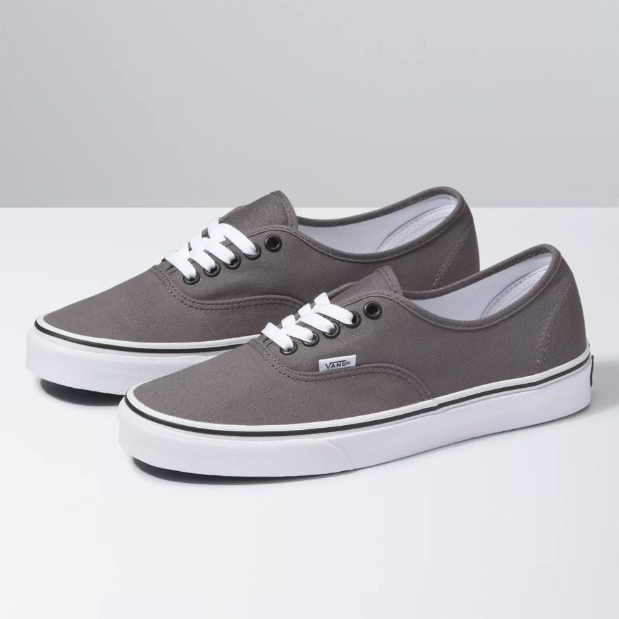 Pair of gray sneakers with white laces on a light gray background