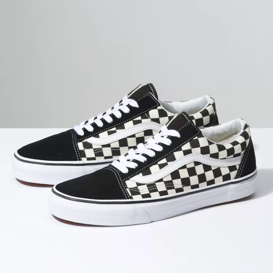 Pair of black and white checkered sneakers on a gray background