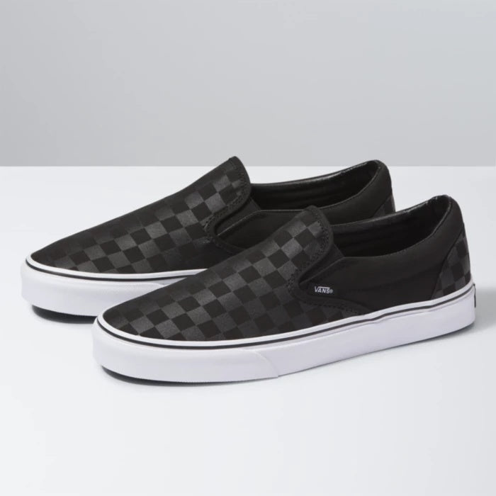 Black checkered slip-on shoes with white soles on a light gray background