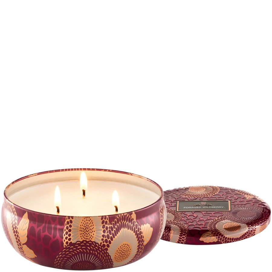 Decorative candle with floral design and matching lid on a white background