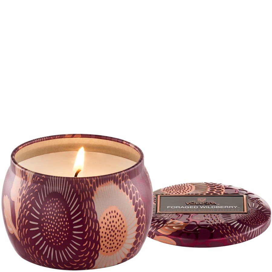 Scented candle in a decorative tin with a visible brand label on a white background