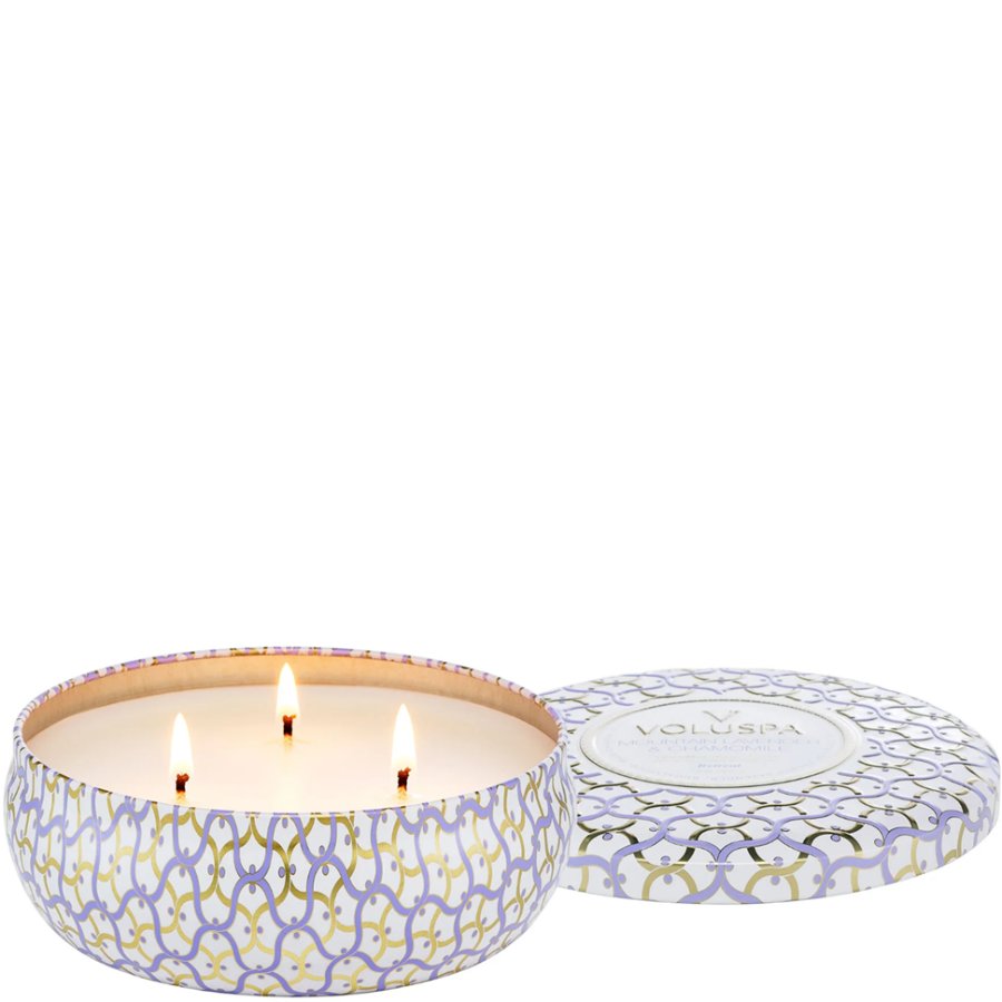 Three-wick candle in a decorative tin with a lid on a white background