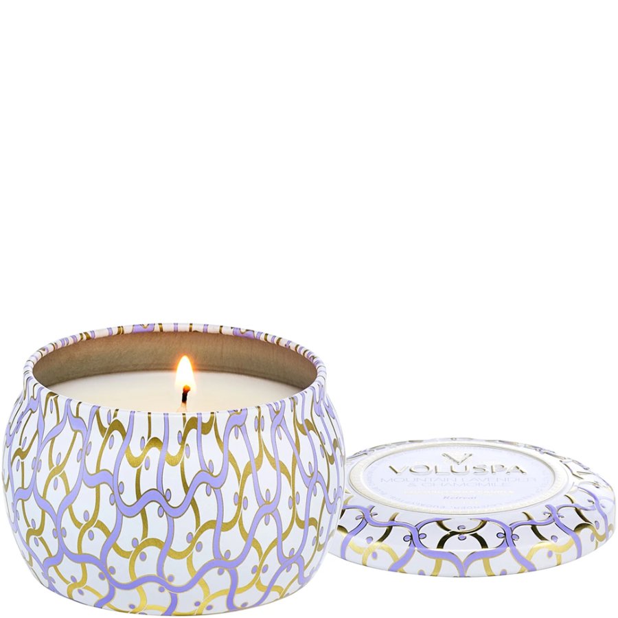Candle in a decorative tin with a visible brand logo on a white background