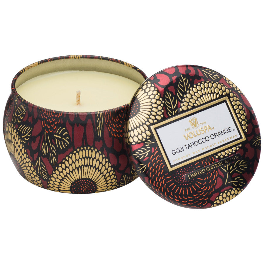 Decorative candle in a patterned container with a visible brand label on a white background