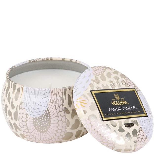 Decorative candle in a patterned container with Voluspa branding on a white background