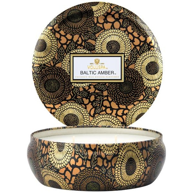 Decorative candle in a patterned tin with 'Vollersa Baltic Amber' branding.