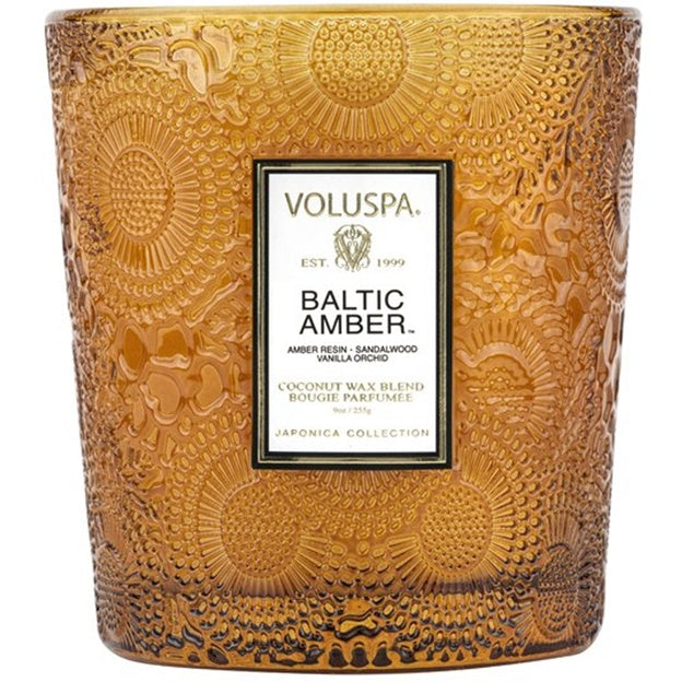 Decorative candle with embossed design and Voluspa label on a white background