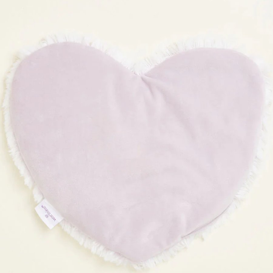 Light purple heart shaped pillow with white label on a light beige background