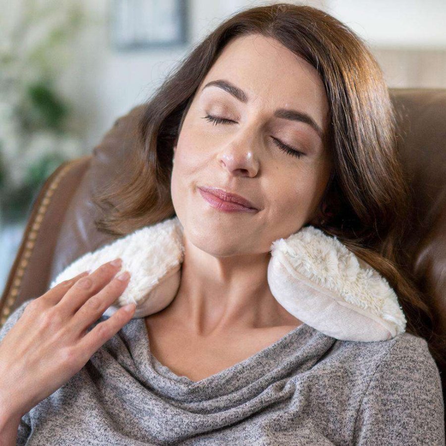 Woman wearing a white neck pillow with a blurred indoor background