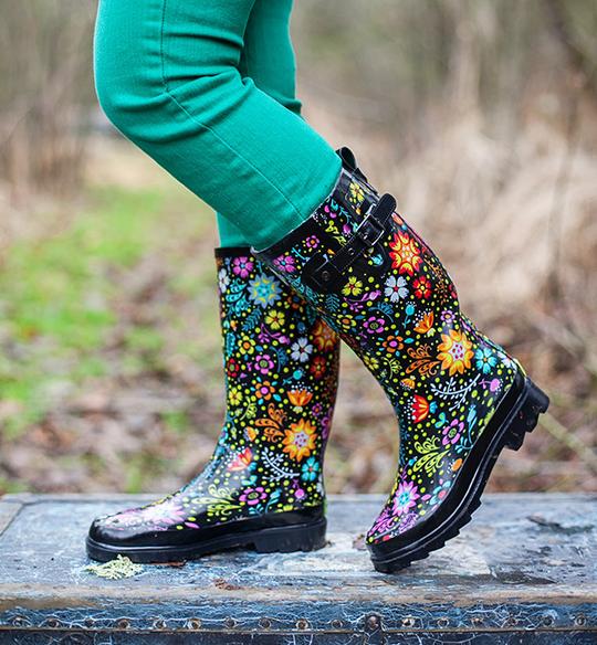 Colorful floral-patterned rain boots on a wooden surface with a blurred natural background.