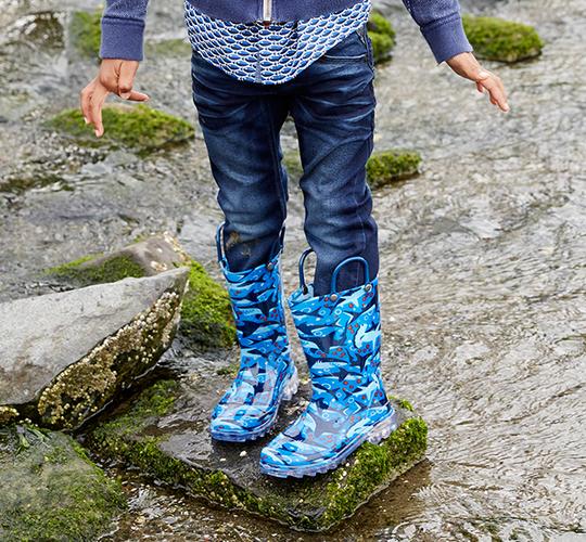 Person wearing blue camouflage boots standing on a rocky surface.
