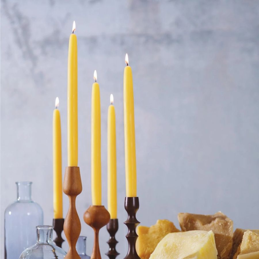 Yellow candles in wooden candlesticks with a neutral background