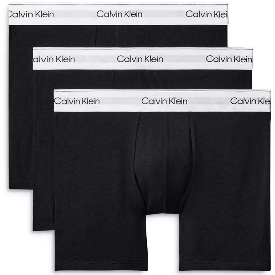 Three pairs of Calvin Klein black boxer briefs arranged in a staggered stack, showing the brand name printed on the waistband.