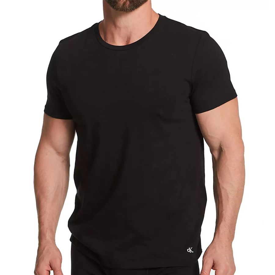 A man wearing a black short-sleeve crew neck t-shirt, shown from the chin down against a plain white background.