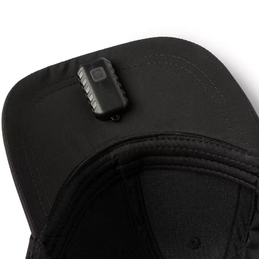 Close-up of a black cap with a small electronic device attached to the side on a white background.