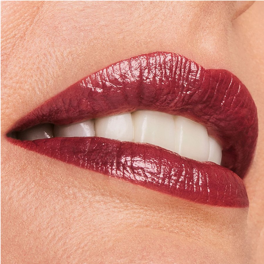 Close-up of a person wearing a glossy red lipstick on a neutral background