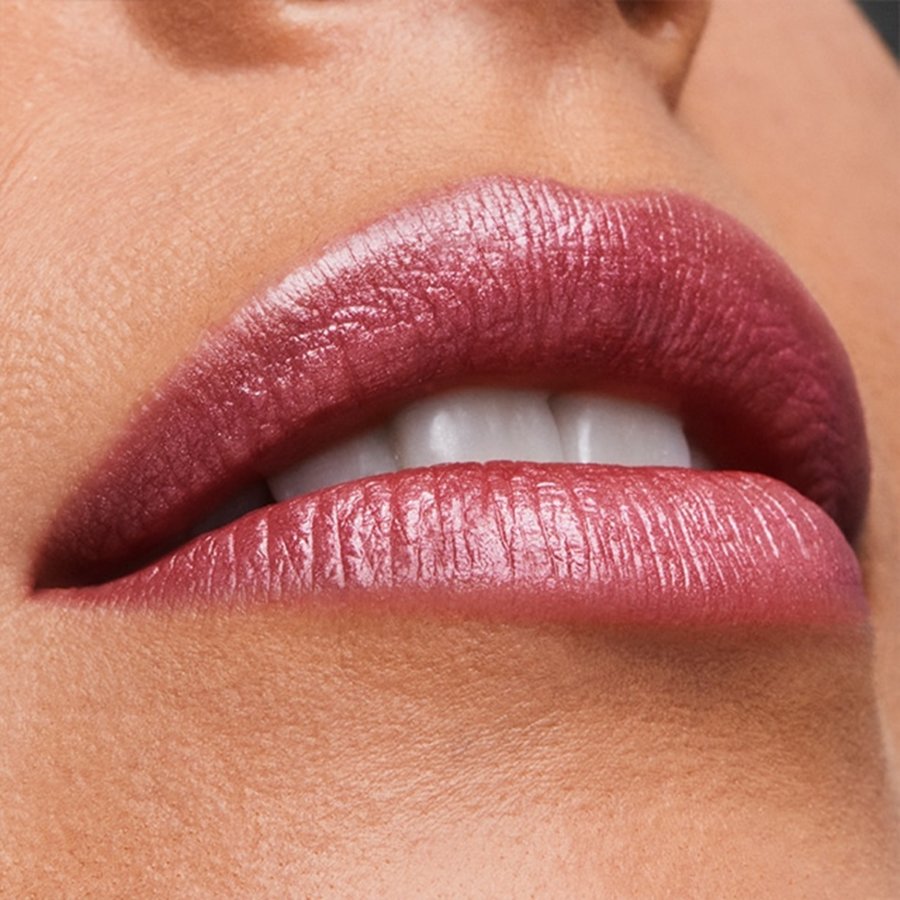 Close-up of a person's lips with a glossy pink lipstick on a neutral background