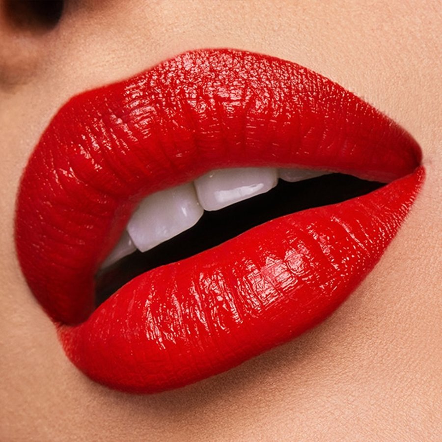 Close-up of a person's mouth with bright red lipstick on a neutral background