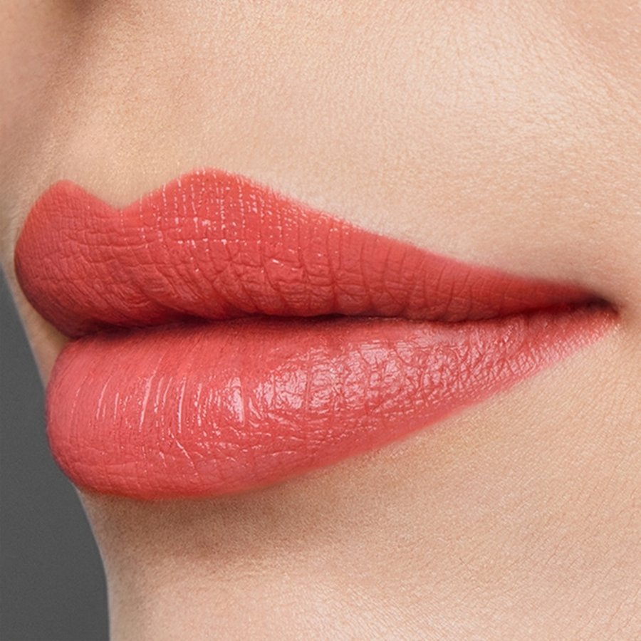 Close-up of a person's lips wearing a coral lipstick on a neutral background