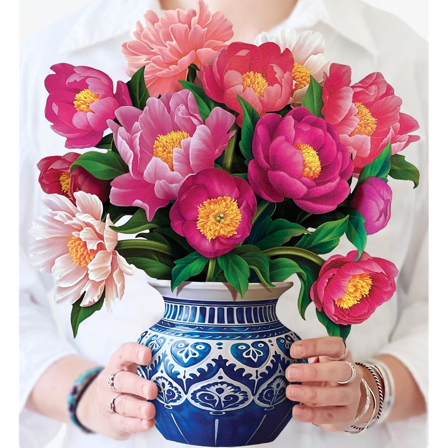 Person holding a blue and white vase with pink flowers