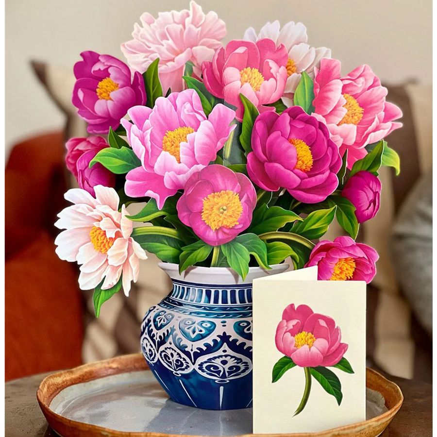 Bouquet of pink and purple flowers in a blue and white vase with a matching card on a wooden surface.