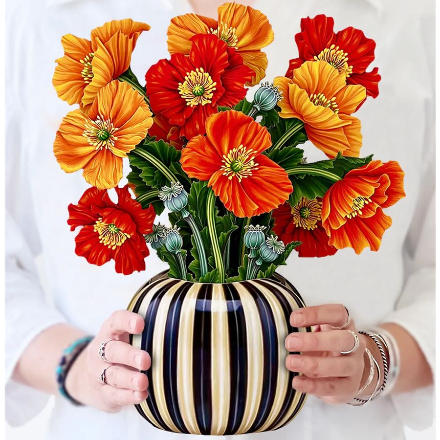 Bouquet of orange and red flowers in a striped vase held by a person.