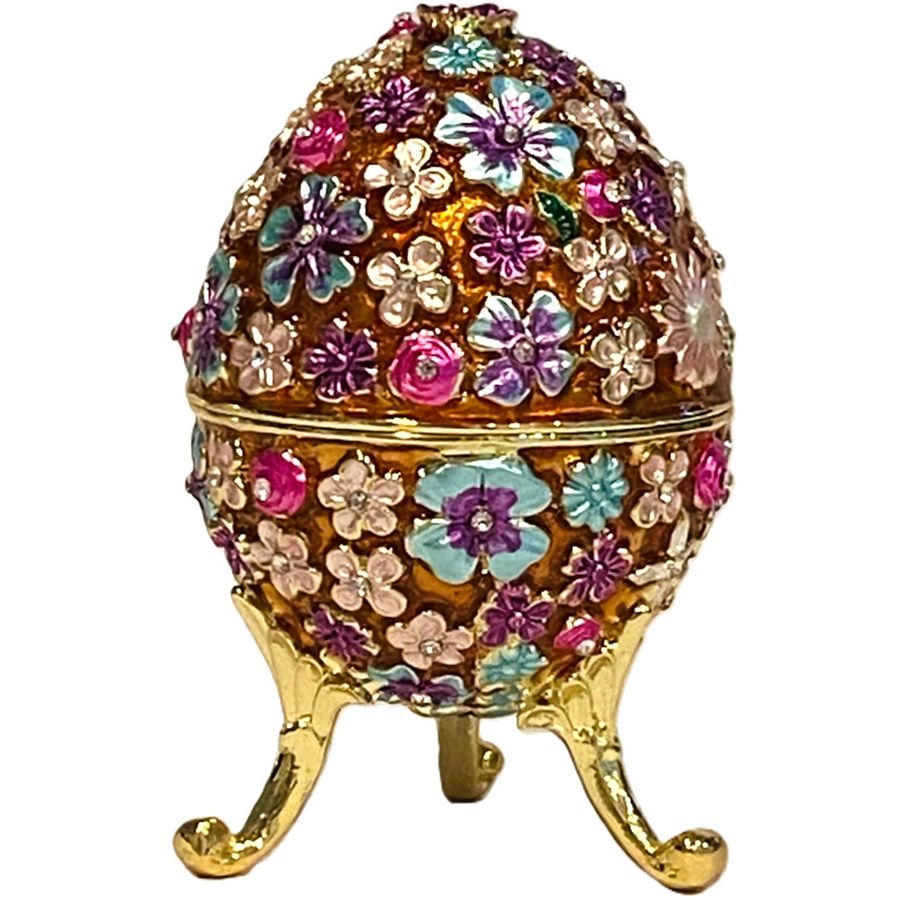 An ornate decorative egg-shaped container with a gold-tone base and legs, covered in colorful floral enameled details in pink, purple, blue, and white on a white background.