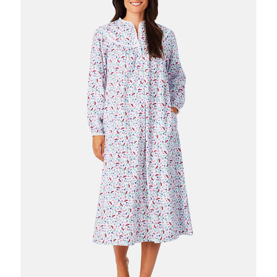Woman in floral print long-sleeve nightgown with button-front and pockets, reaching mid-calf.